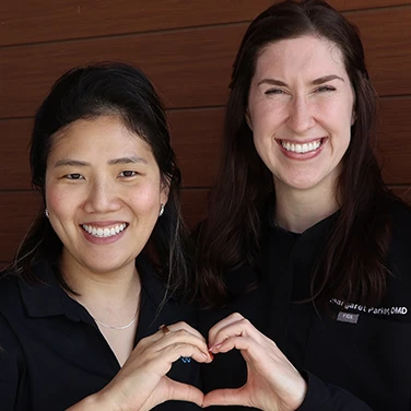 Dr. Park and Dr. Parker making a heart with their hands at Singing River Dentistry in Muscle Shoals, AL.