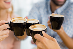 close up of four people holding cups of coffee and making a toast