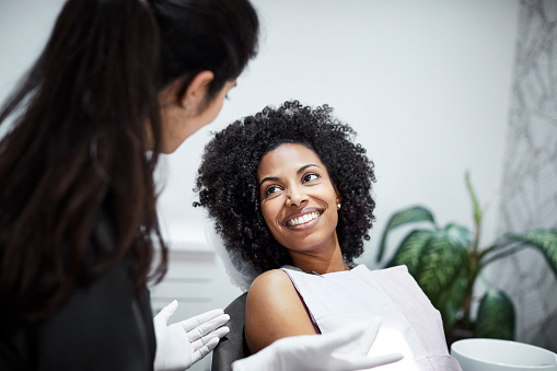 Dentist discussing technology with smiling female patient at Singing River Dentistry in Madison, AL Dentist discussing technology with smiling female patient at Singing River Dentistry in Madison, AL