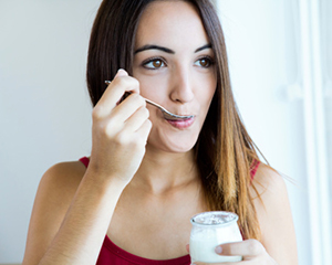 Woman eating yogurt snack before appointment at Singing River Dentistry in Athens, AL