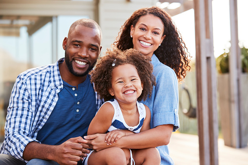  smiling two parents with their happy young child