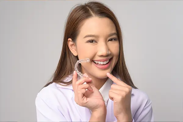 smiling teen holding an Invisalign tray