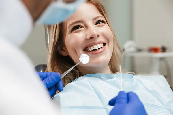 Patient happily waiting in a dental chair for her dentist to begin her routine dental exam
