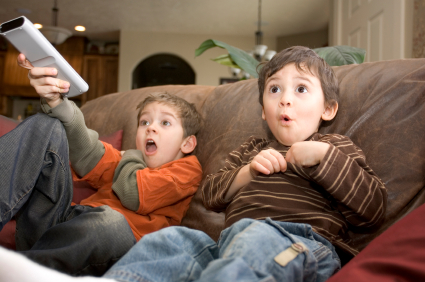 two kids watching tv on the couch and making funny faces