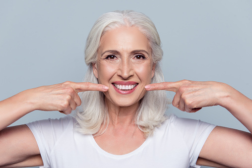 smiling older female pointing to her mouth