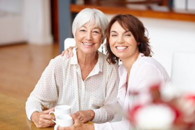 Women smiling while one holds a cup of coffee Women smiling while one holds a cup of coffee
