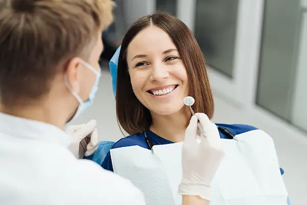 Woman smiling at her dentist during a routine dental exam, emphasizing the comfort of professional dental care.